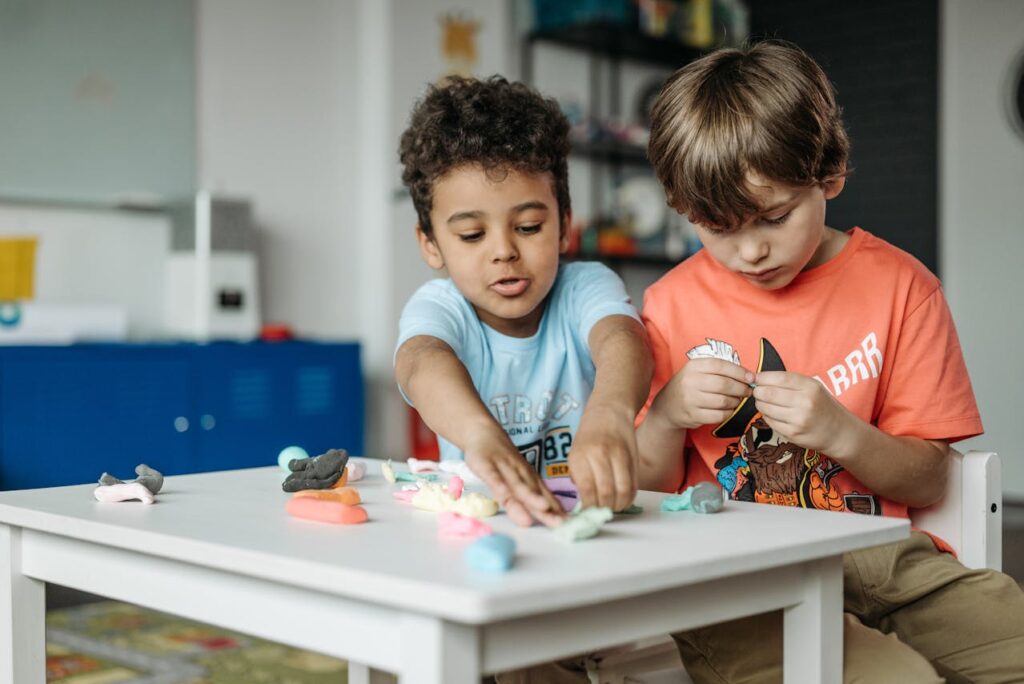 Two children at a low table playing with clay--an activity found to boost basic math and spatial intelligence.