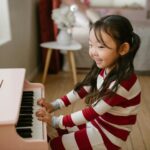 A young girl on a small pink piano