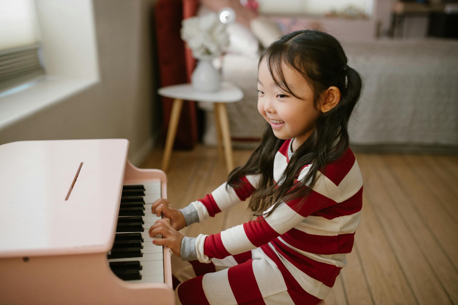A young girl on a small pink piano